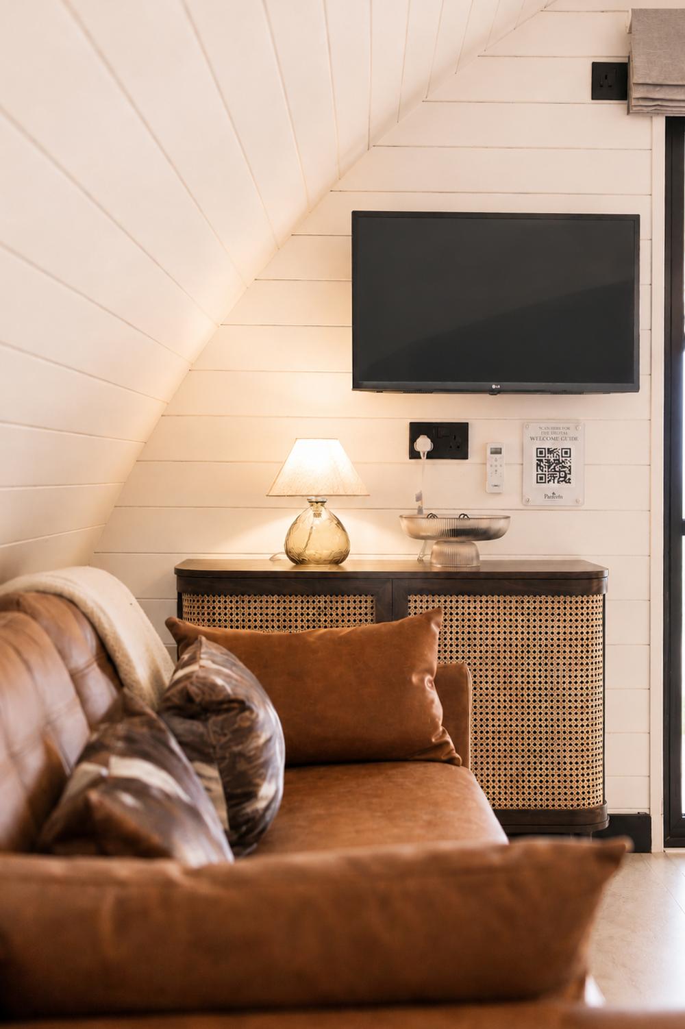 Leather sofa and wall-mounted TV beneath the vaulted timber ceiling
