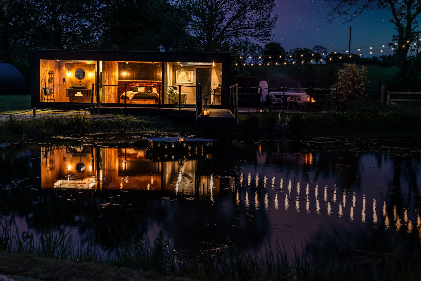 The Rusty Boathouse reflected perfectly in the private lake at night, Pantcefn