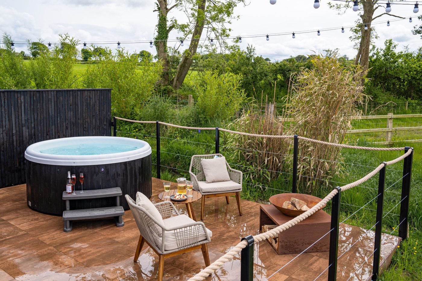 Hot tub and corten fire bowl on the Rusty Boathouse deck with rope-rail and countryside