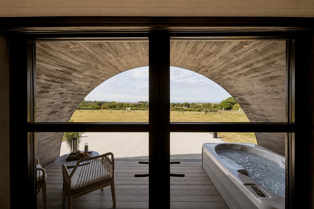 View through the glass doors to the hot tub, deck and open farmland beyond