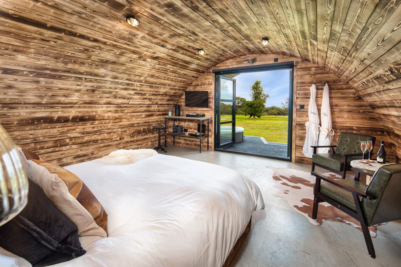 The Piglet Pod interior with bi-fold doors open to the countryside and hot tub