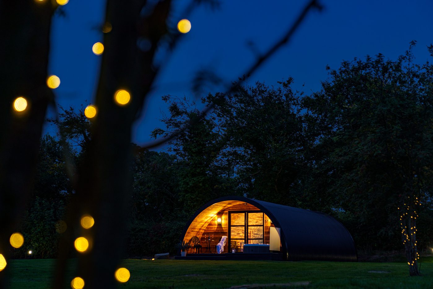 The Piglet Pod glowing through fairy lights at night under the trees, Pantcefn