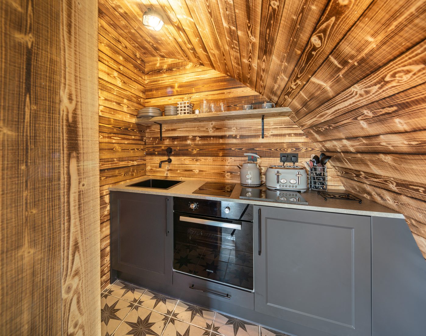 Kitchen inside the Piglet Pod — warm amber glow and timber interior