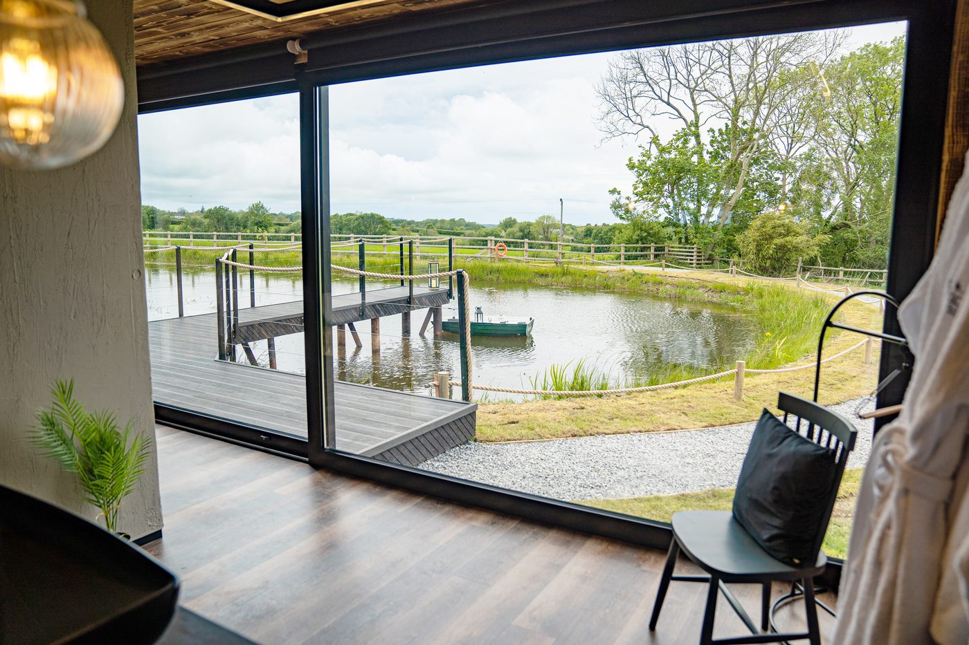 View through the floor-to-ceiling glass of the Rusty Boathouse to the lake and jetty